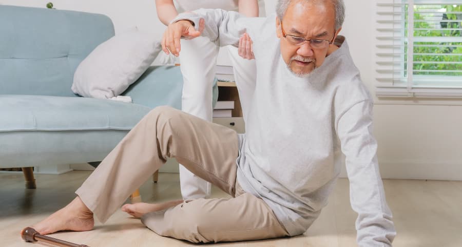 An older man getting helped off the floor